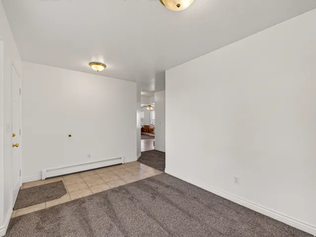 White walls, flush mount ceiling lighting, and a combination of carpet and tiled flooring