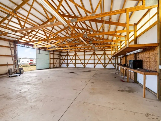 Spacious interior with exposed wood beam ceiling, concrete flooring, and built-in workbench