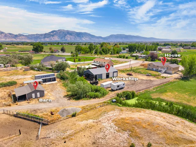 Expansive rural property featuring a primary residence, detached workshop with storage, and traditional barn structure