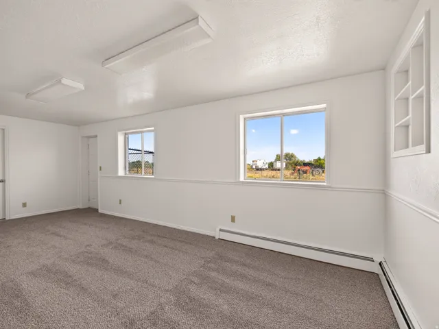 Carpeted flooring, white walls, and two windows