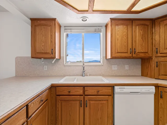 Wood-finish cabinetry with dark bronze hardware, laminate countertops, and a double basin sink with a chrome faucet