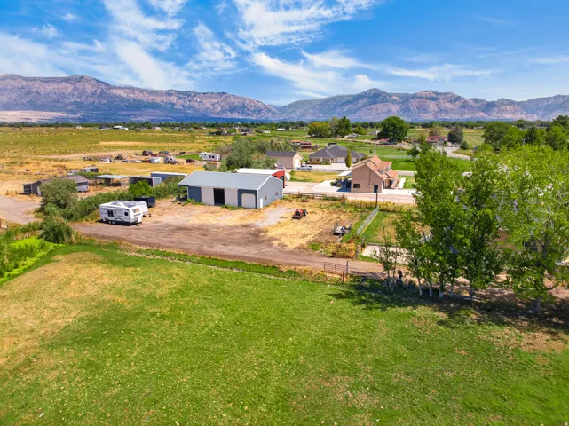 Expansive property featuring a metal outbuilding, gravel driveway, and a partially fenced perimeter