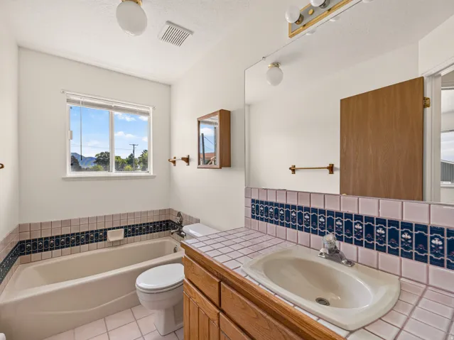 Bathroom featuring a built-in tub, tiled vanity, and a window with natural light