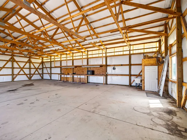 Spacious interior with exposed wood beam framing, concrete flooring, and built-in workbench