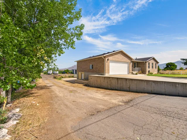Brick exterior with a white garage door, concrete retaining wall, and a paved driveway