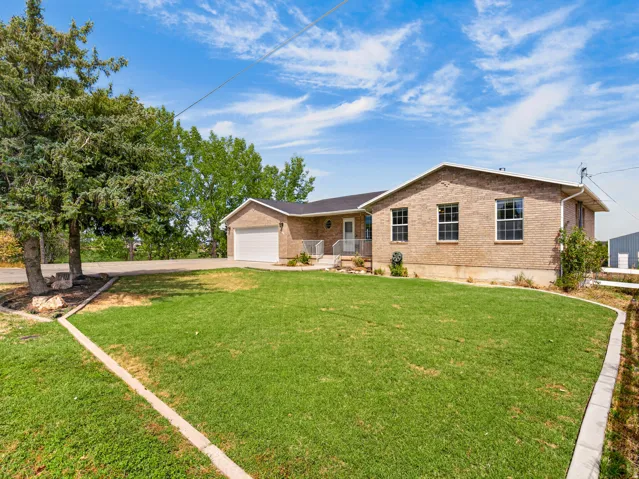 Brick exterior with white trim, attached garage, concrete driveway, and front lawn