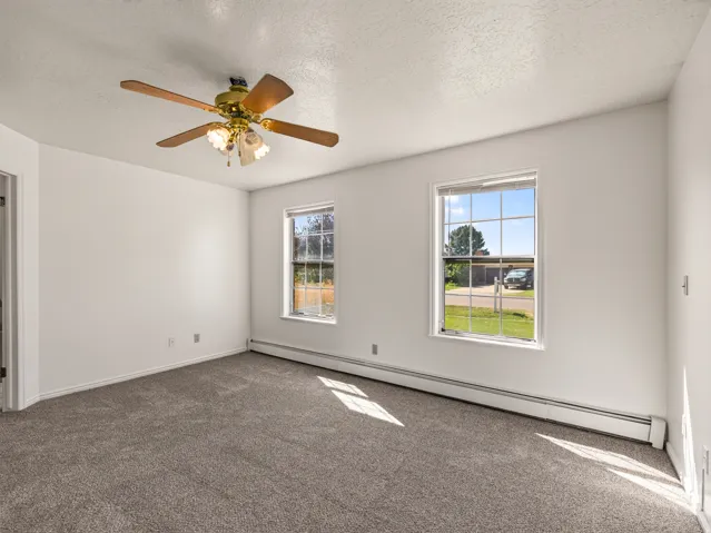 White walls with textured ceilings, gray carpeting, and two windows