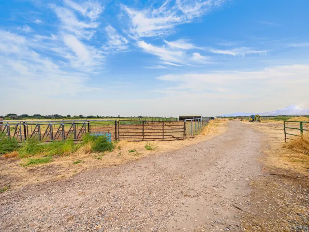 Gravel pathway leading to fenced areas and an agricultural structure