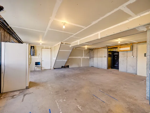 Spacious unfinished basement with exposed concrete walls, concrete flooring, and ceiling-mounted lighting fixtures