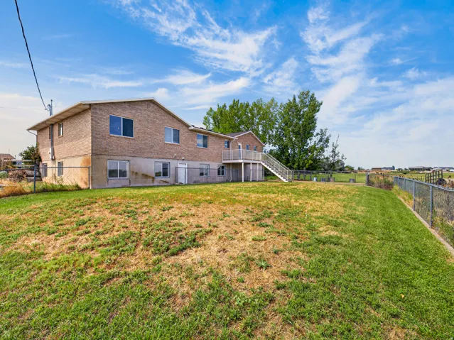 Brick exterior, multiple windows, upper-level deck, exterior stairs, sloped lawn