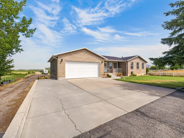 Brick exterior residence with an attached garage, paved driveway, and manicured lawn