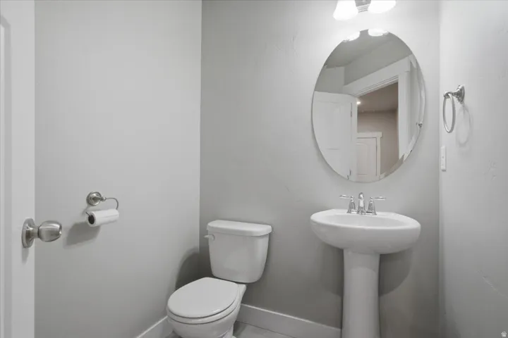 Pedestal sink with chrome faucet, oval wall mirror, and brushed nickel hardware