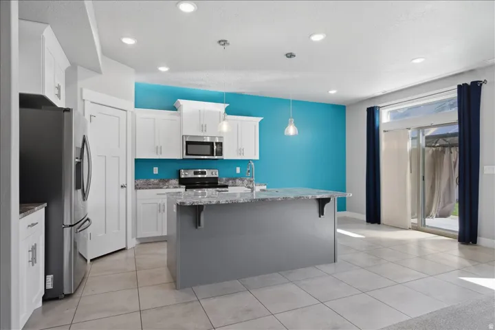 Kitchen featuring white cabinetry, stainless steel appliances, a center island with countertop, and tile flooring