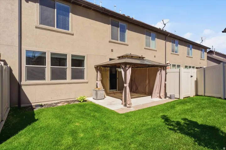 Private backyard with a concrete patio, covered gazebo, and a manicured lawn