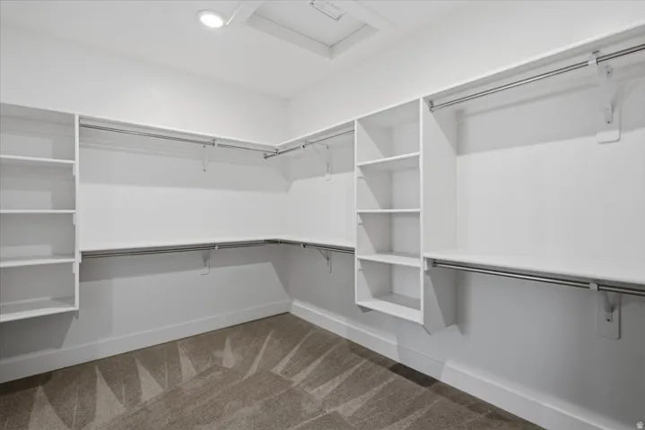 Integrated shelving system with multiple hanging rods, built-in shelving units, and recessed lighting