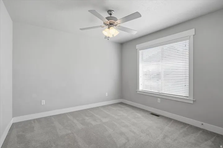 Carpeted flooring, light gray wall finishes, window with blinds, and a ceiling fan with light fixture