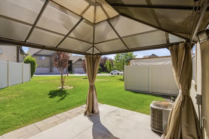 Concrete patio with paver accents, covered by a metal-framed gazebo with privacy drapes