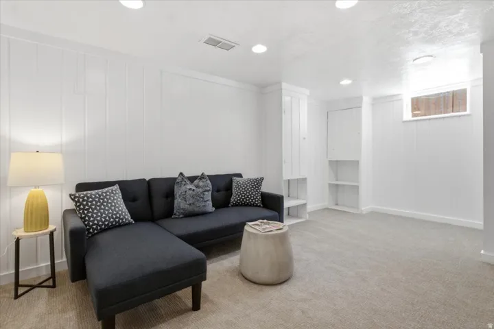 Finished basement flex room for family room, large bedroom or office featuring recessed lighting, white shiplap walls, closet and built-in shelving cabinetry.