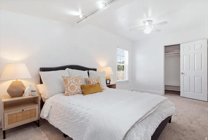 Carpeted master bedroom featuring fresh carpet and paint, ceiling fan with integrated lighting, and two closets.