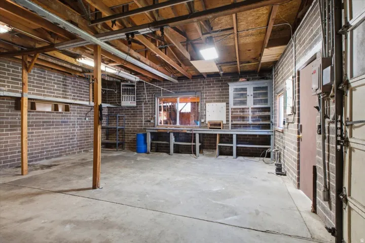 Spacious garage workshop with concrete floor, exposed brick walls, ample storage, heater and a built-in workbench.