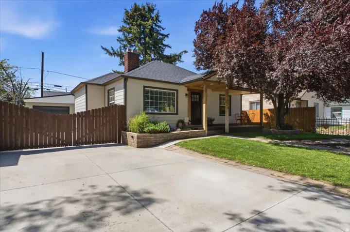 Concrete driveway bordered by a wood privacy fence and brick retaining wall, creating a defined front and side yard.
