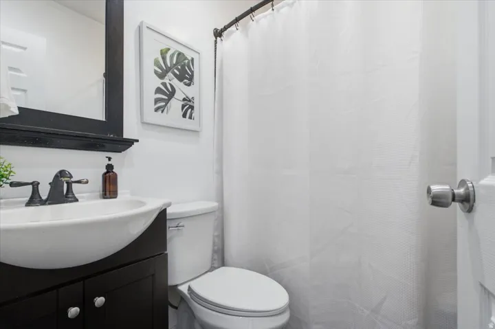 Bathroom vanity featuring an integrated white sink, dark wood-finish cabinetry, and a coordinating dark-framed mirror.