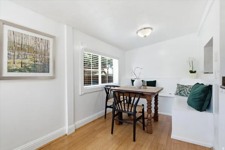 Warm interior featuring wood-finish flooring, built-in bench seating, white window blinds, and a semi-flush mount light fixture.
