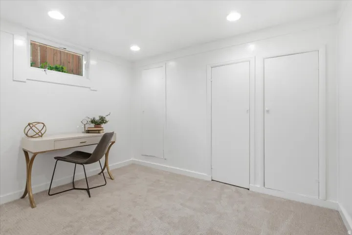 Basement bedroom with ample closet space,  recessed lighting, new carpet flooring, and a horizontal window with wood trim.