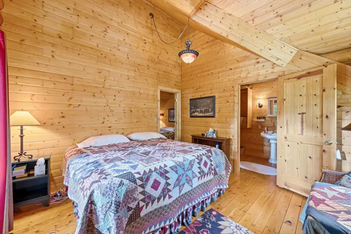 Wood paneling throughout, exposed wood beam, wood-finish flooring, and a pedestal sink