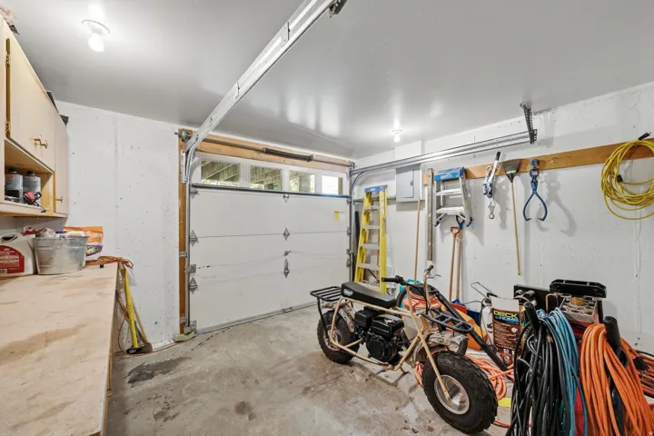 Attached garage with concrete flooring, overhead lighting, and white paneled garage door