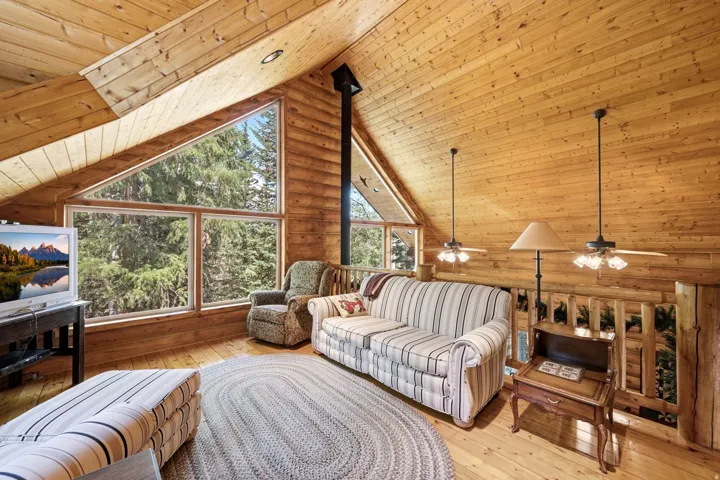 Vaulted wood-paneled ceilings, natural wood walls, extensive window installation, and wood-finish flooring