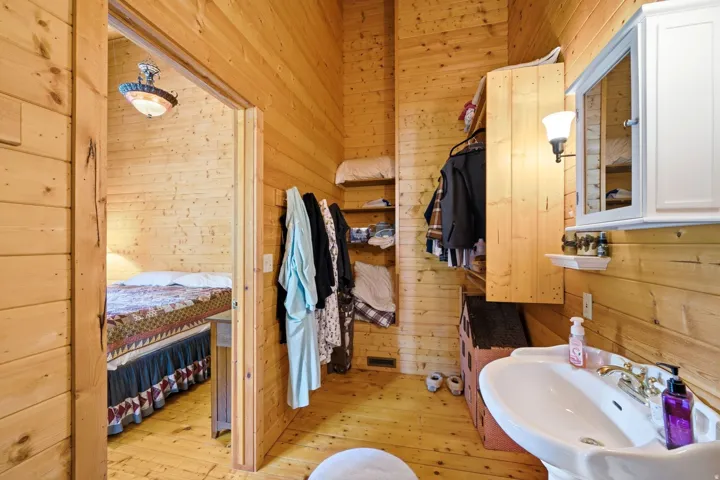 Wood-paneled room featuring a pedestal sink with a brass-finish faucet, a wall-mounted medicine cabinet with an integrated light fixture, and built-in shelving