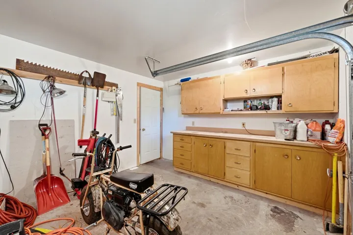 Garage with concrete flooring, extensive built-in cabinetry, and integrated workbench