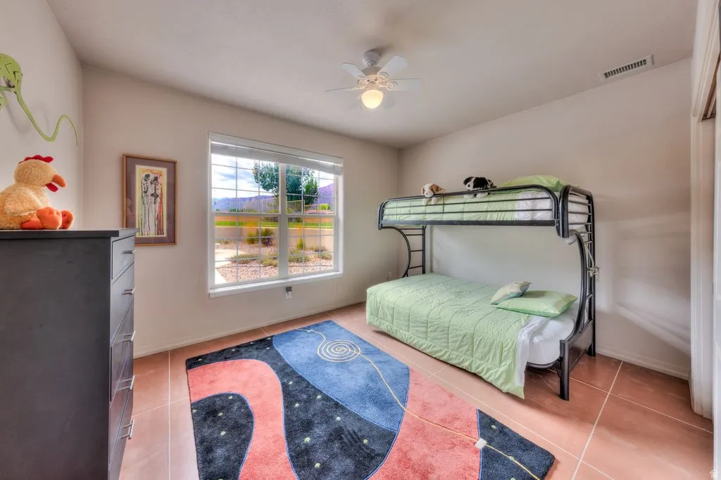 Spacious room featuring tile flooring, a large window with horizontal blinds, and a ceiling fan with integrated lighting