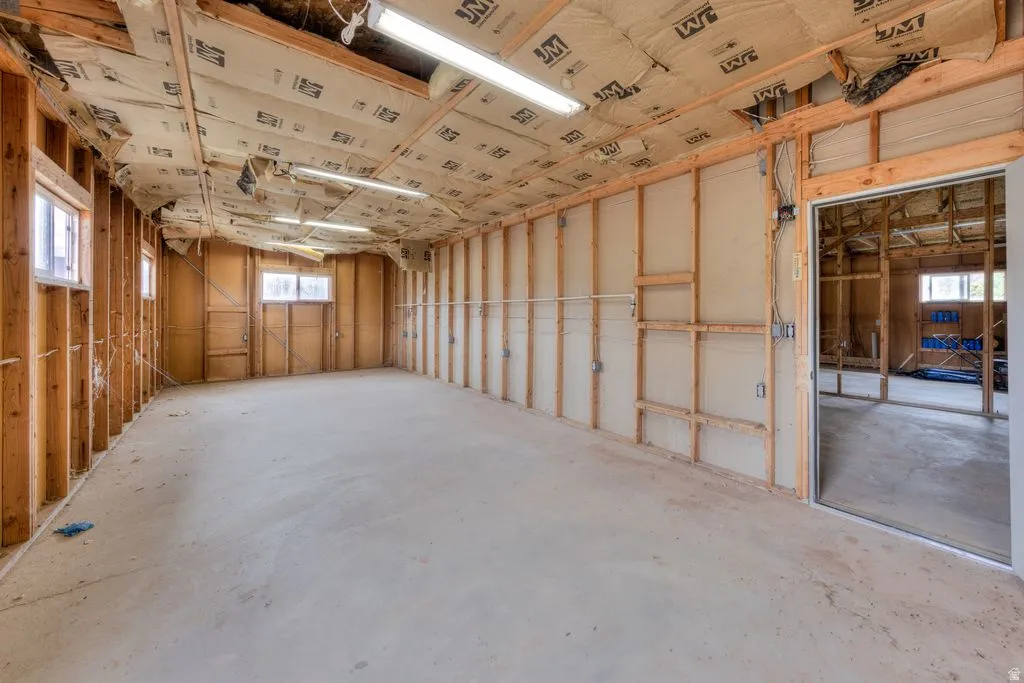 Concrete flooring throughout, exposed wood framing, multiple windows, and fluorescent lighting