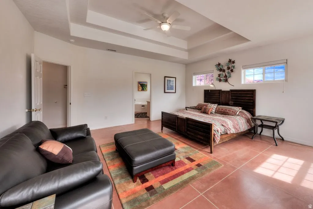 Tray ceiling with a ceiling fan, two transom windows, and durable flooring