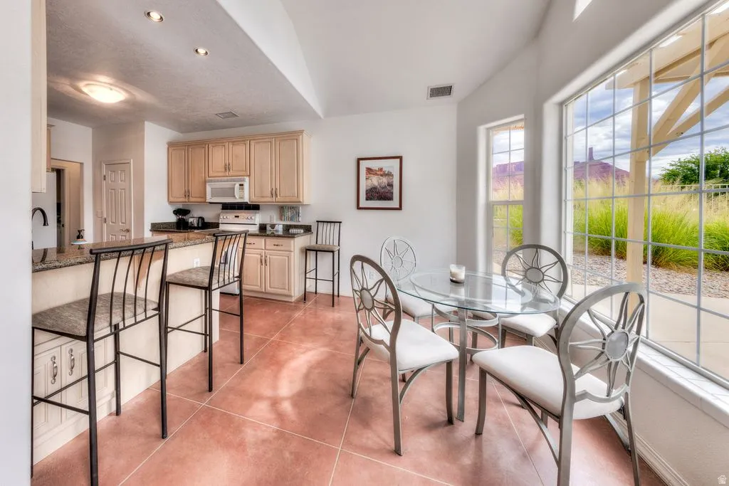 Kitchen with light wood-finish cabinetry, granite-style countertops, and integrated appliances