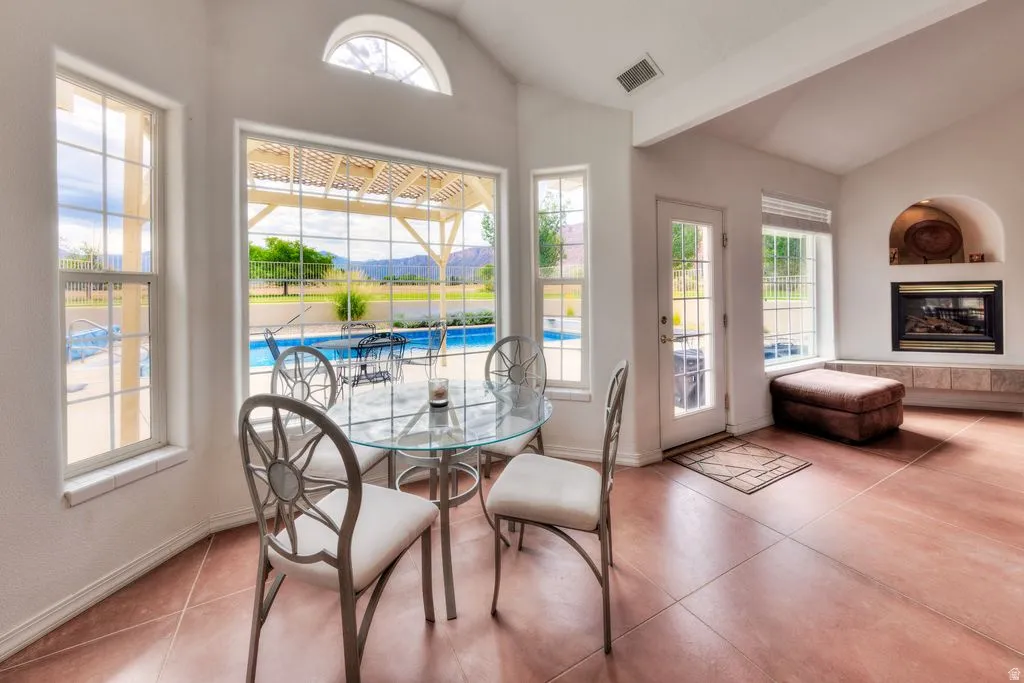Vaulted ceilings with an arched window, a fireplace with an arched niche, a glass-paned door, and tiled flooring