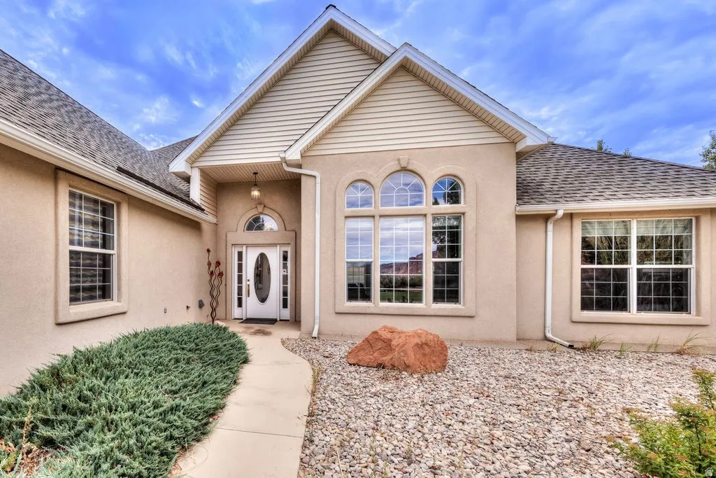 Stucco exterior with gabled roofline, arched entry, decorative front door with oval glass insert, and large arched windows