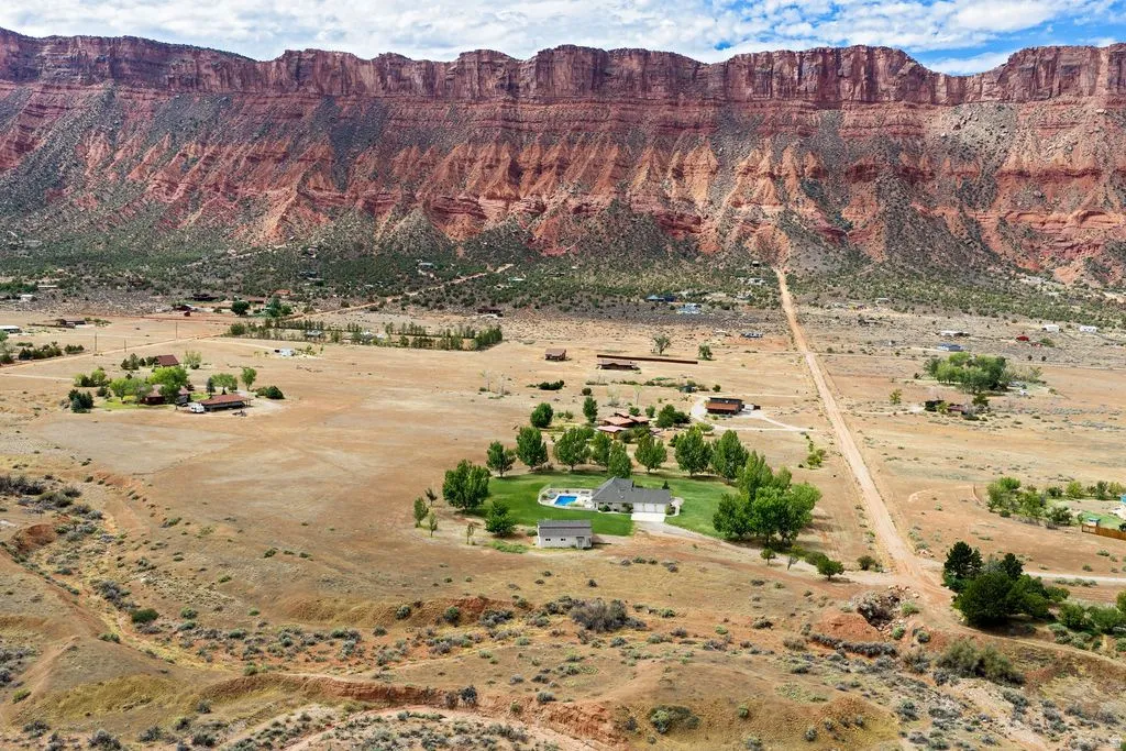 Expansive property featuring a large residence, detached structure, inground swimming pool, and mature landscaping, all against a dramatic natural backdrop