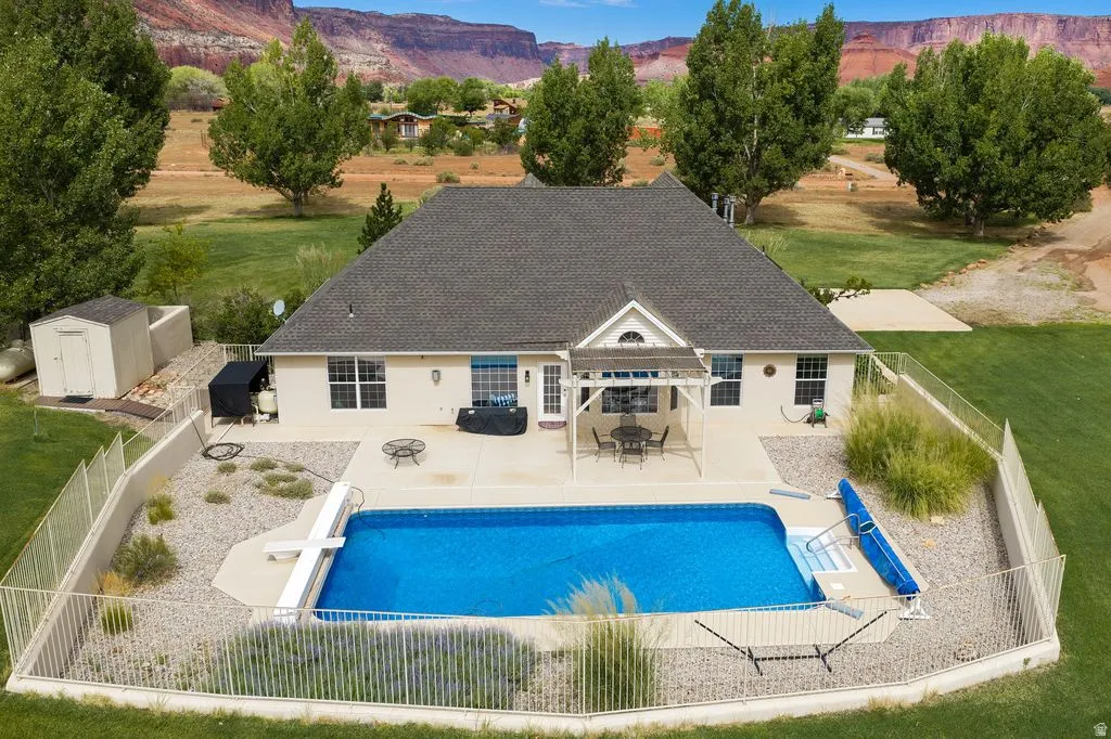 Expansive private yard featuring a swimming pool, concrete patio, and pergola