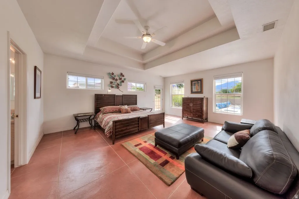 Recessed ceiling, ceiling fan, multiple windows, tile flooring, and a glass-paneled door