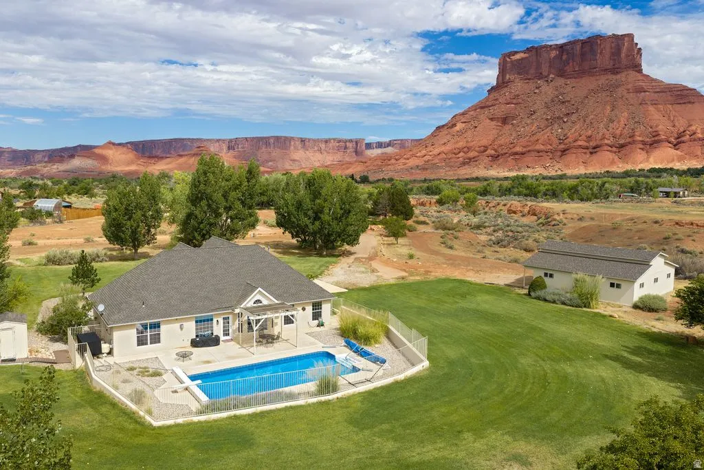 Single-story residence with a rectangular pool, fenced patio area, and an expansive lawn