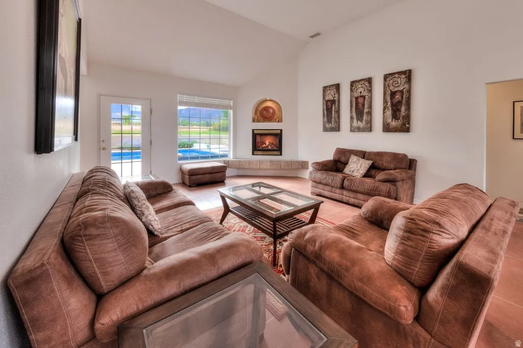 Vaulted ceilings, tiled flooring, built-in fireplace with hearth, and a glass-paned door