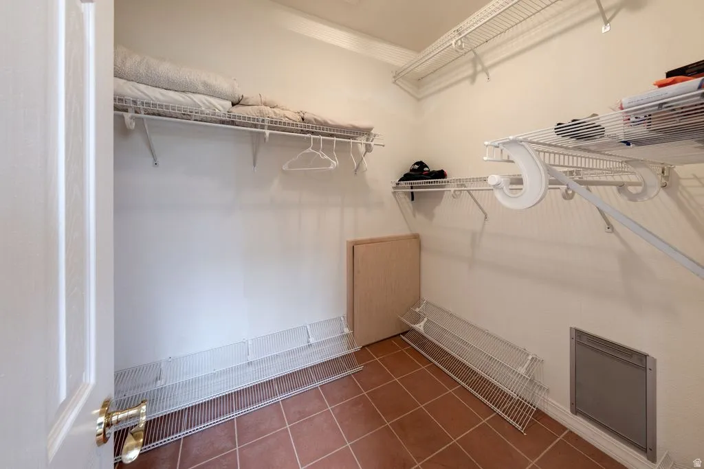 White wire shelving system, terracotta-style floor tiles, and a white paneled door with brass hardware