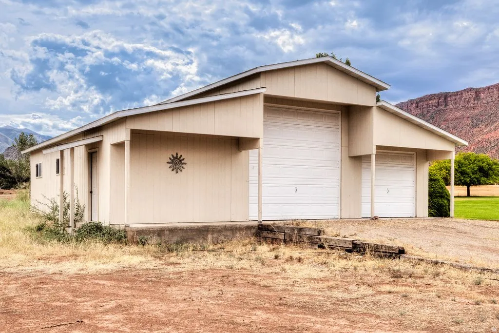 Barn-style structure featuring two roll-up garage doors, a side entry door, and a covered porch area