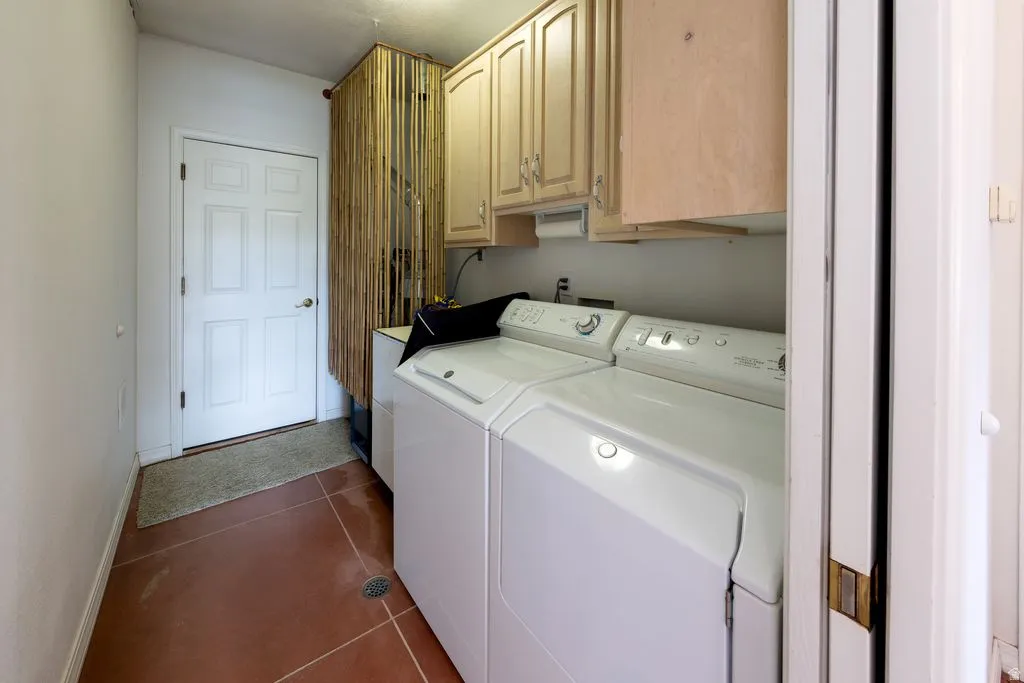 Laundry area with white paneled door, terracotta-toned flooring, and upper cabinetry