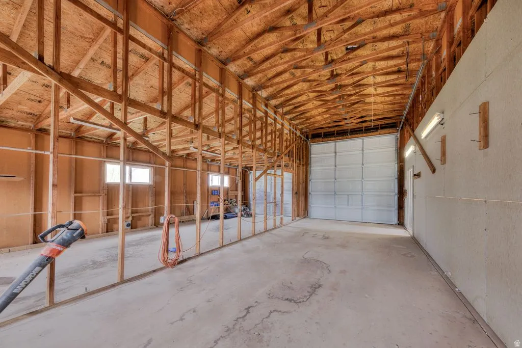 Spacious interior with exposed wood framing, concrete flooring, and a large roll-up door