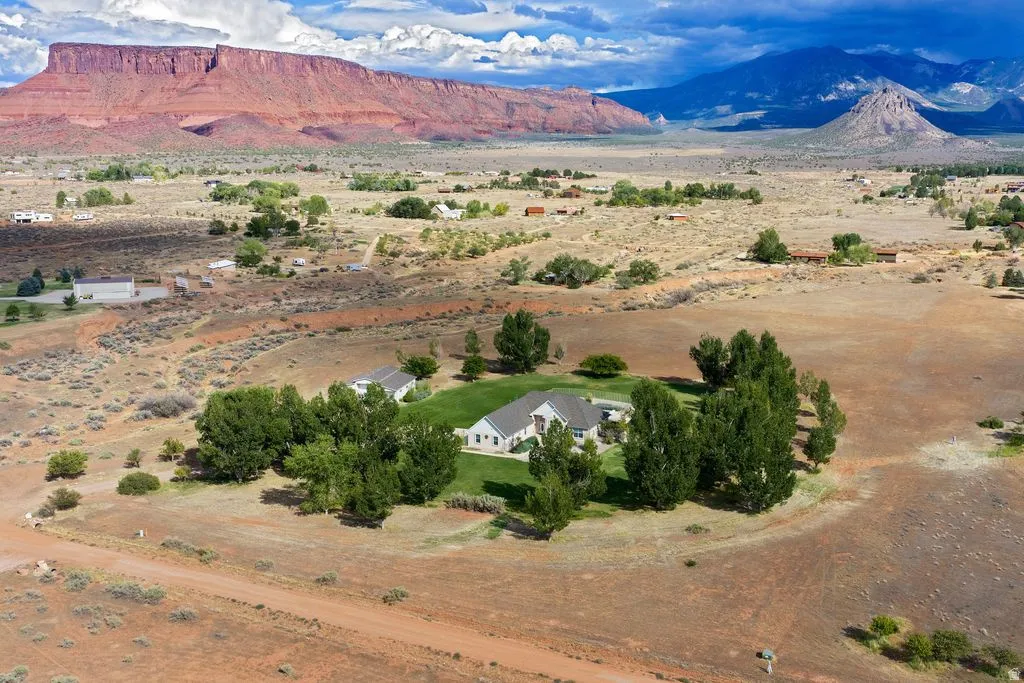 Expansive property with a white exterior residence, surrounded by mature trees and manicured lawn areas
