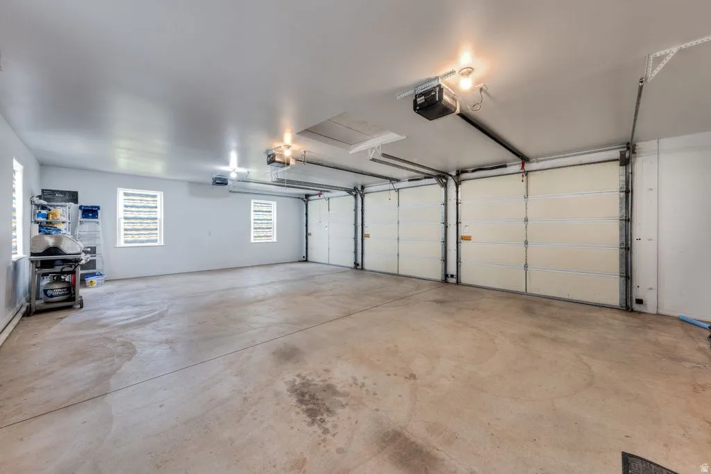 Spacious garage featuring a concrete floor, two garage doors with openers, and multiple windows for natural light